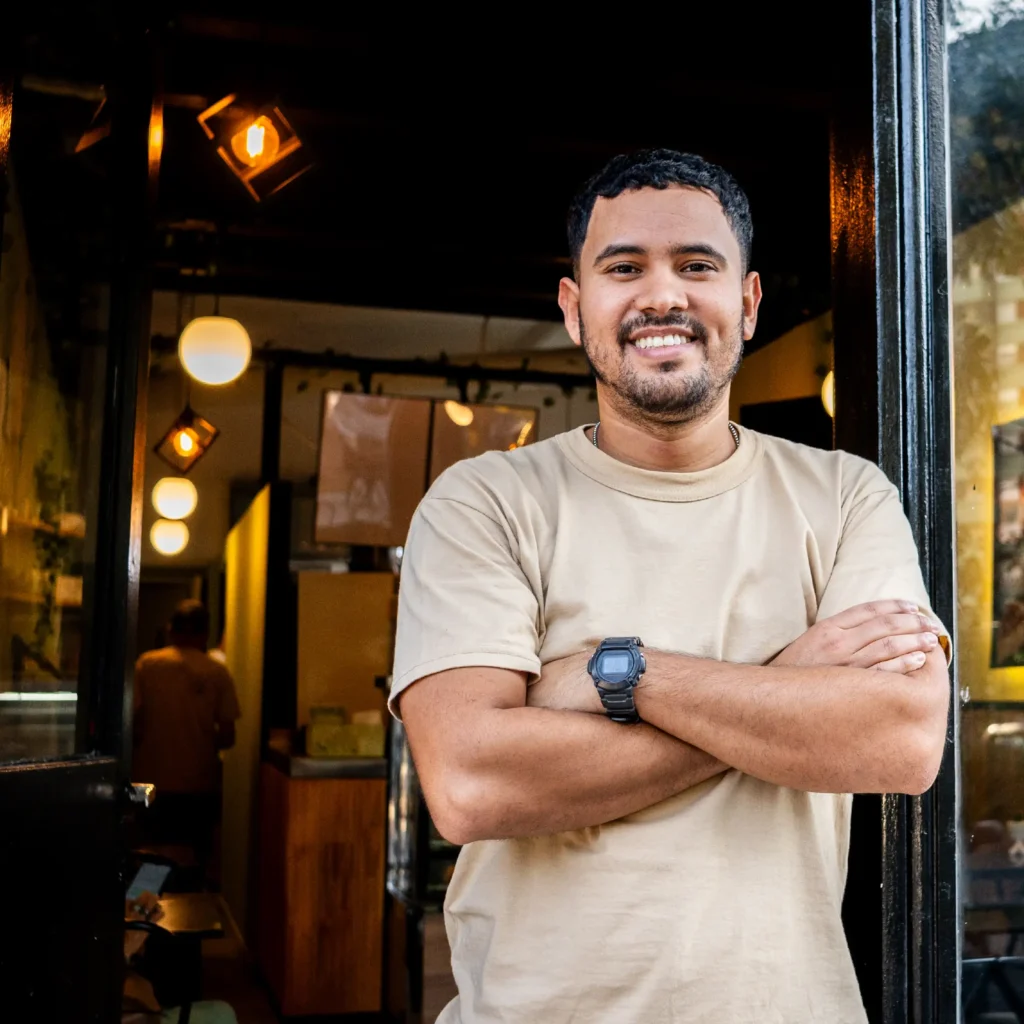Man looking at camera outside his own shop