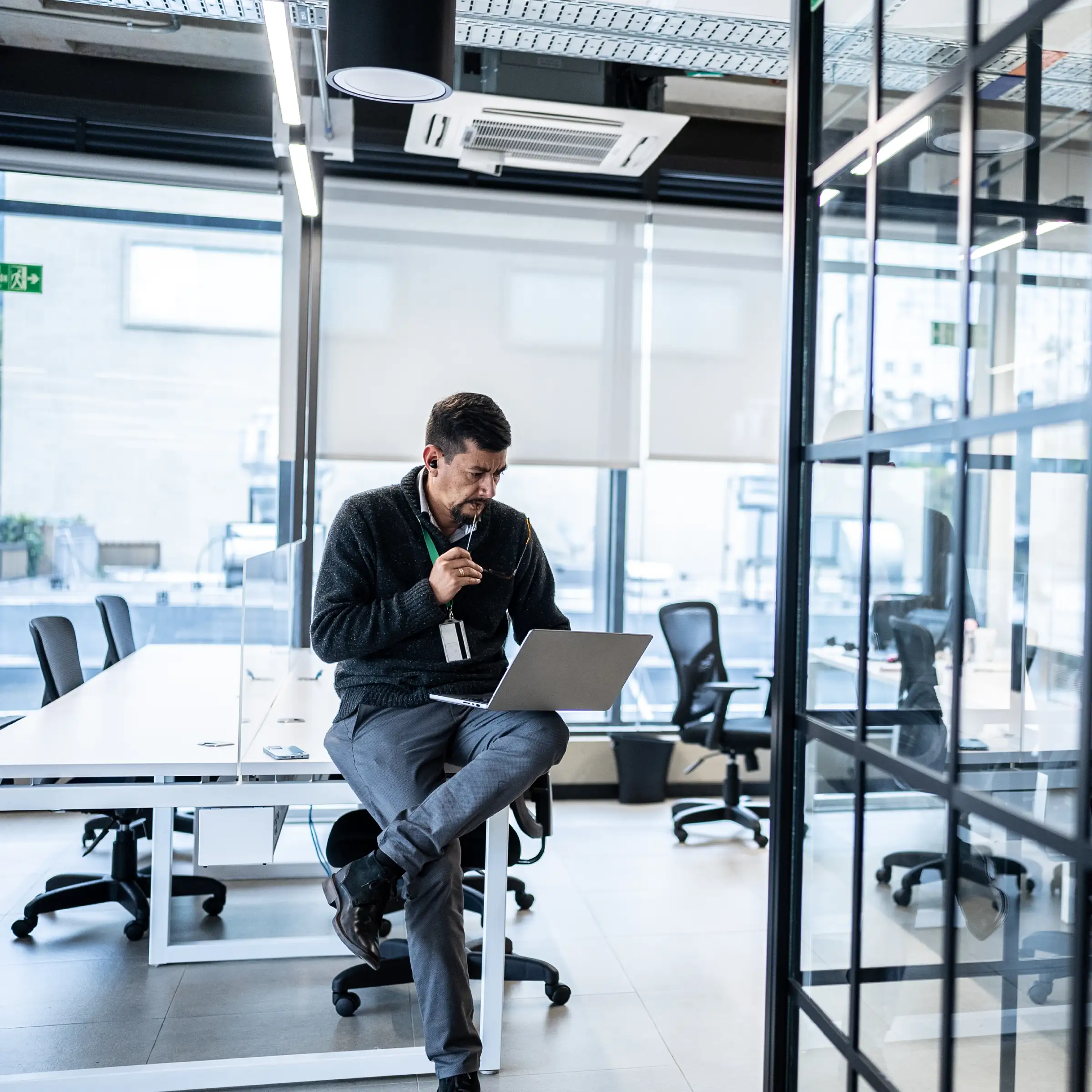 Man sitting on desk looking at laptop